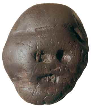 A small pebble with three indents that create the impression of a face